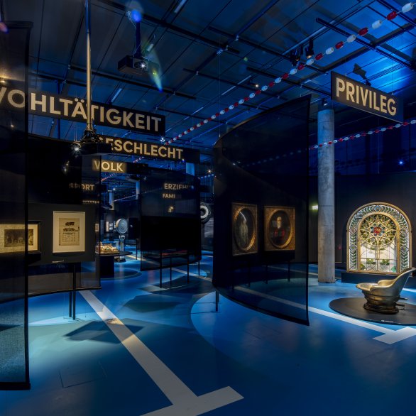 Blick in die Ausstellung. Zu sehen ist eine Sitzbadewanne, fürstliche Gemälde und ein prunkvolles Fenster.