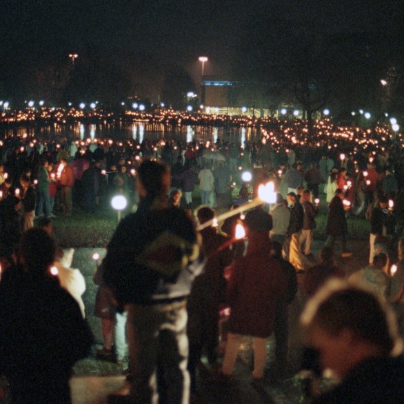 Man sieht eine Menschenkette im Dunklen. Die Menschen halten Lichter in den Händen.