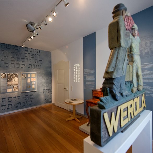 Blick auf Wandtexte und Exponate sowie ein Schild der Werola im Jüdischen Dokumentationsraum