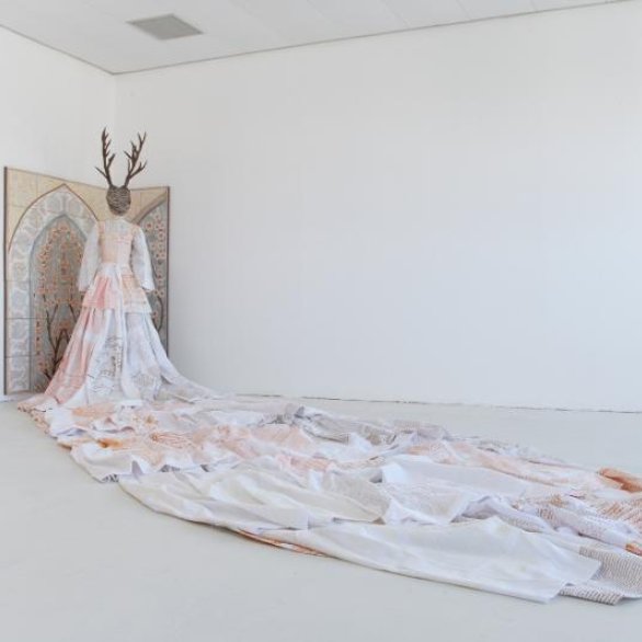 Figur mit einem Kleid mit sehr langer Schleppe und Geweih auf dem Kopf