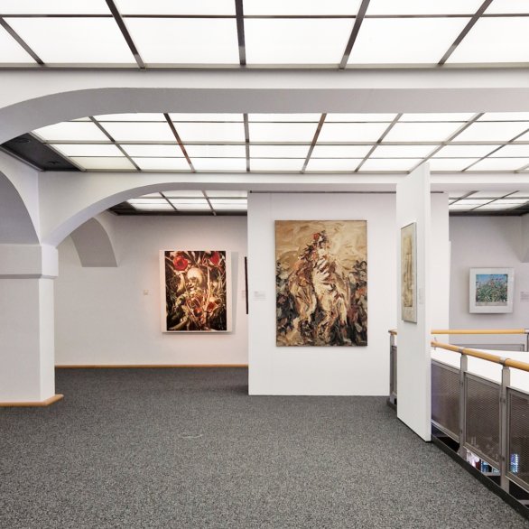 Blick in den Ausstellungsraum mit verschiedenen Gemälden und Fotografien