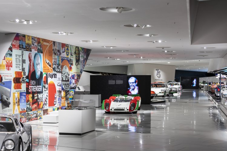 View of the Porsche Museum exhibition, to the left a collage of historical posters.
