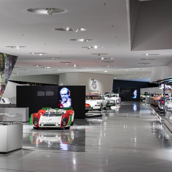 View of the Porsche Museum exhibition, to the left a collage of historical posters.