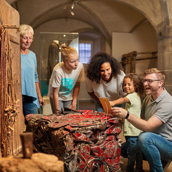 Familie vor der ZeitSprung Installation Wertschätzung. Zu sehen ist ein alter Kruschtschrank und dem gegenübergestellt ein Schrottwürfel eines Austos, das im Zuge der "Abfrackprämie" 2009 verschrottet wurde