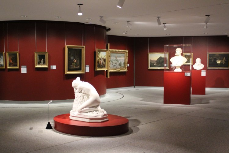 Parcours Beaux-Arts avec des tableaux au mur et des sculptures au coeur de la salle : une femme agenouillée et deux bustes d'homme