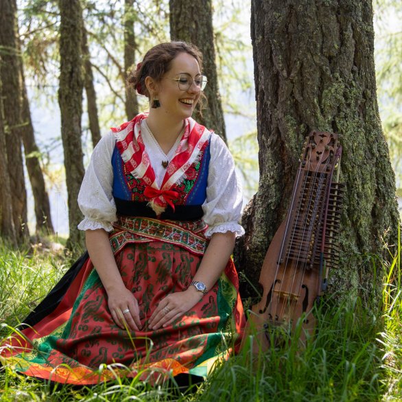 Musikerin Lorène Quinodoz sitzt in idyllischer Waldkulisse