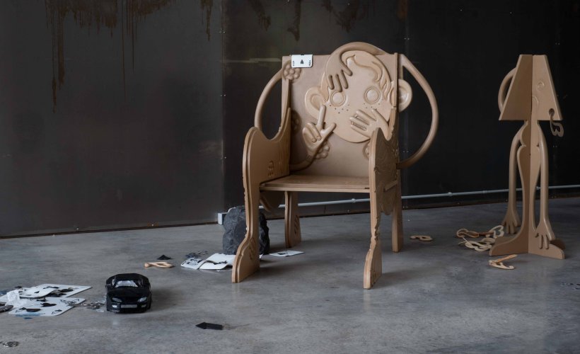 Installation eines geschnitzen Stuhls, Lampe, Spielzeugauto, Papier, und Trümmer