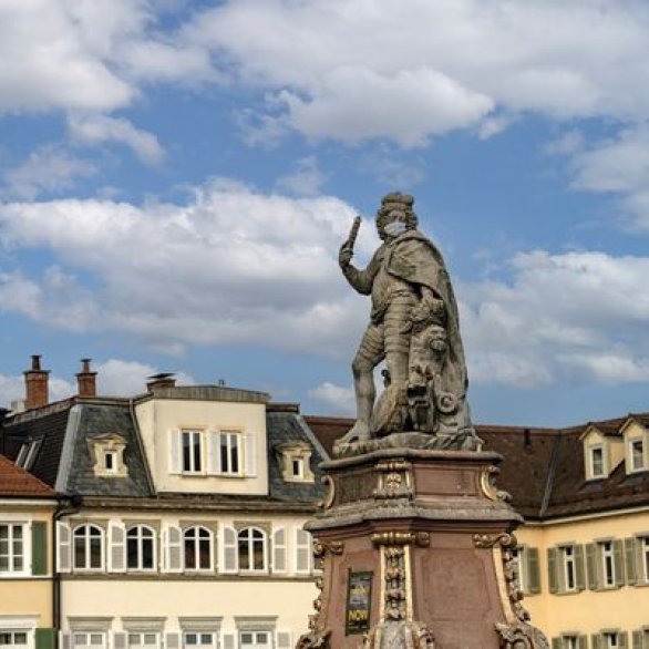 Der Ludwigsburger Markplatz mit Statue in der rechten Bildhälfte. Die Statue trägt einen Mund-Nasen-Schutz