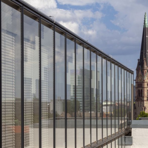 Die Glasfront im sechsten Stock entlang fotografiert mit dem Kirchturm der Lutherkirche im Hintergrund.