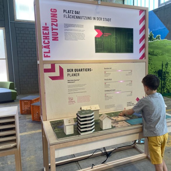 Kind an einem Ausstellungsexponat der Ausstellung grün.stadt.grau